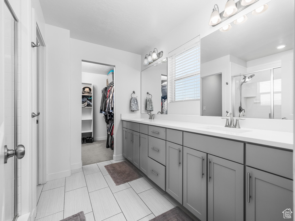 Bathroom with a shower stall, a spacious closet, and double vanity