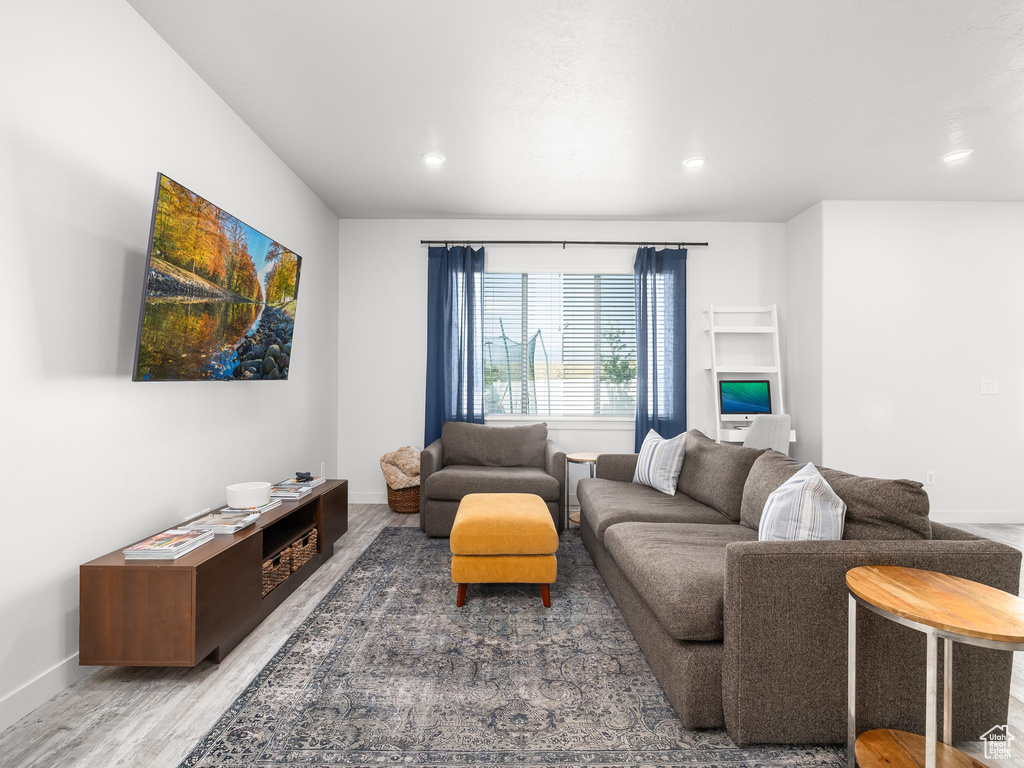 Living room with light wood-type flooring and recessed lighting