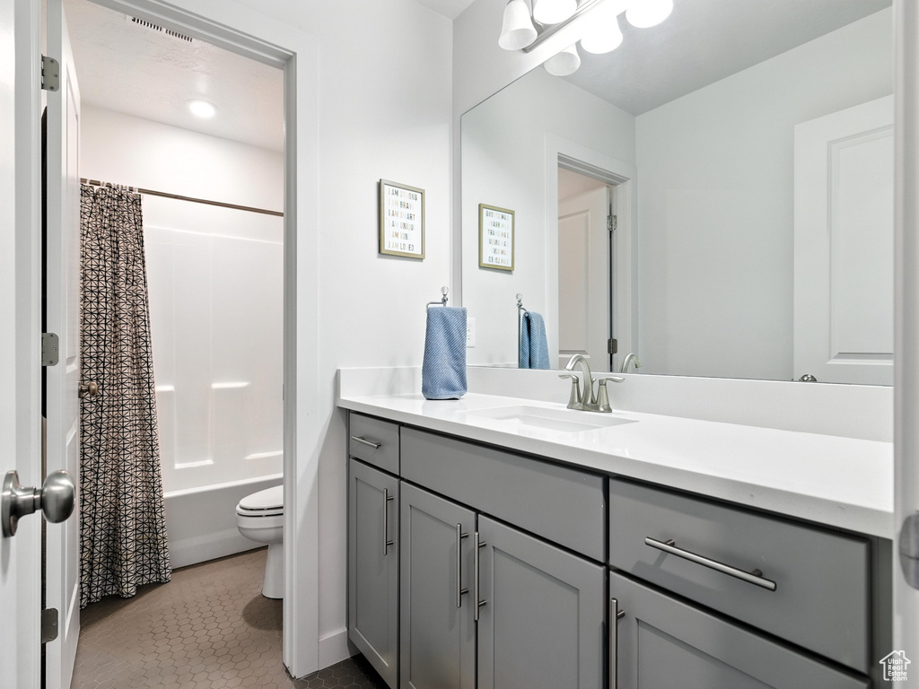 Bathroom featuring vanity, shower / bath combo with shower curtain, and tile patterned flooring