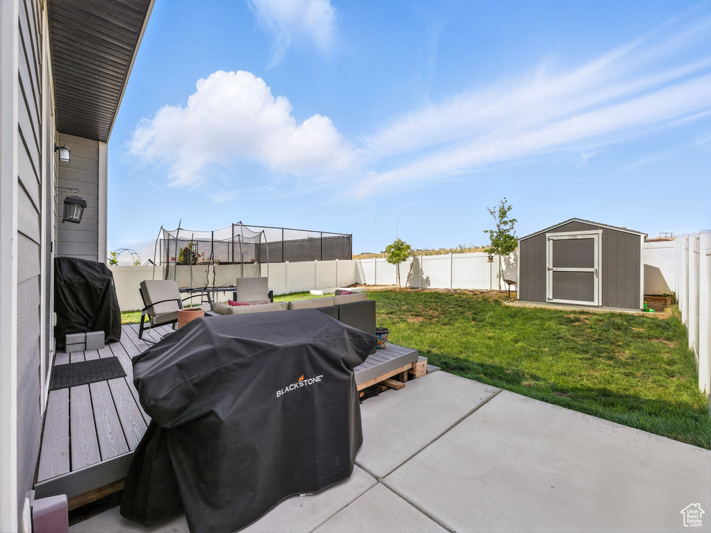 Fenced backyard featuring a trampoline, a shed, area for grilling, and a patio area