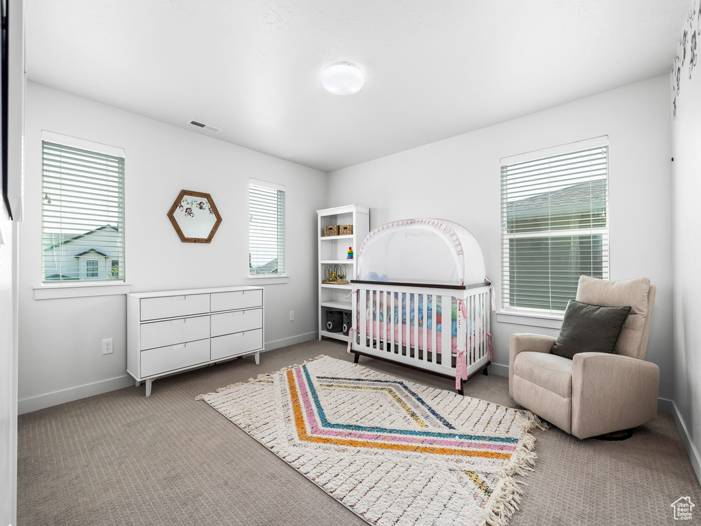 Carpeted bedroom featuring baseboards and a crib