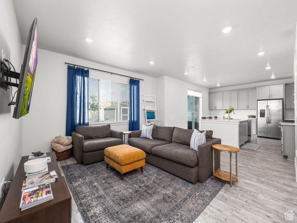 Living room with plenty of natural light, light wood-style flooring, and recessed lighting