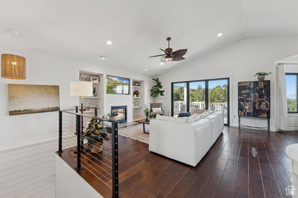 Living room featuring healthy amount of natural light, vaulted ceiling, ceiling fan, recessed lighting, and dark wood-style floors