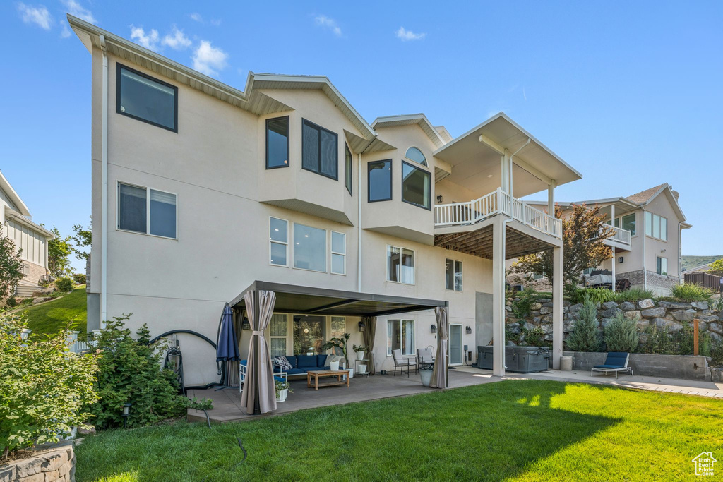 Back of house with an outdoor living space, a patio area, a yard, and stucco siding