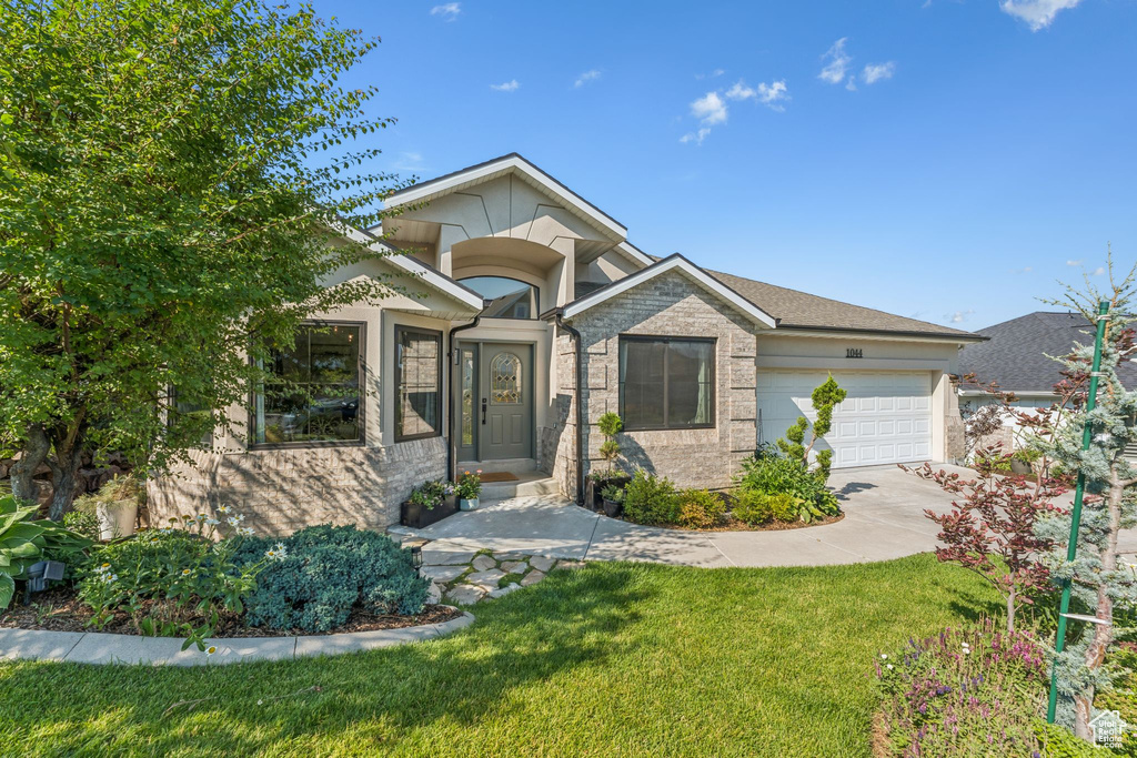 View of front of property with a garage, driveway, and a front lawn