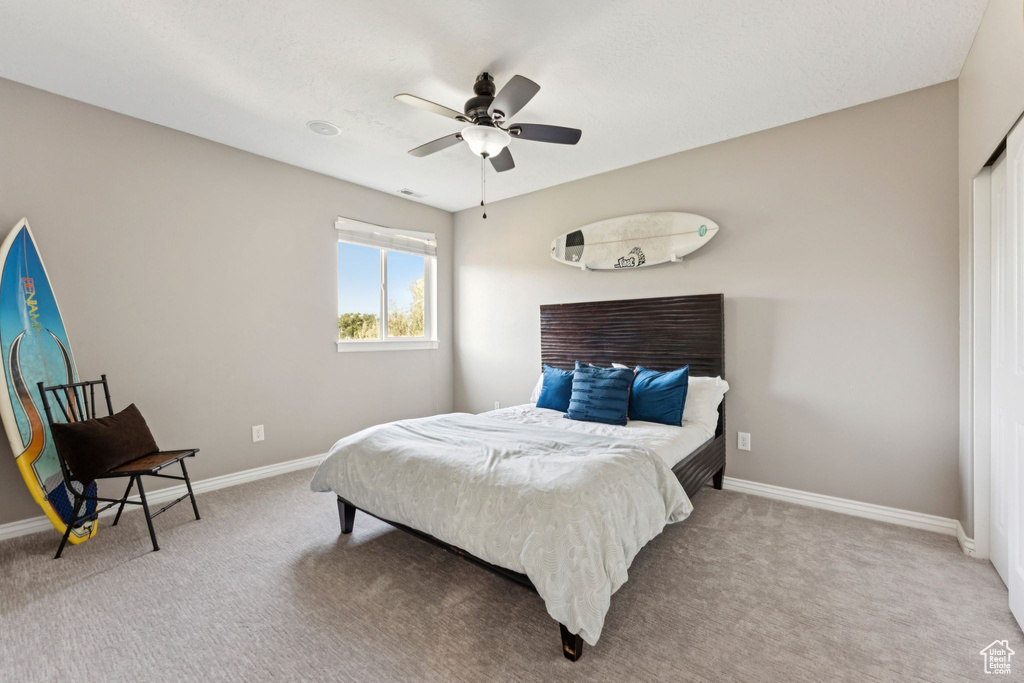 Carpeted bedroom featuring baseboards and ceiling fan