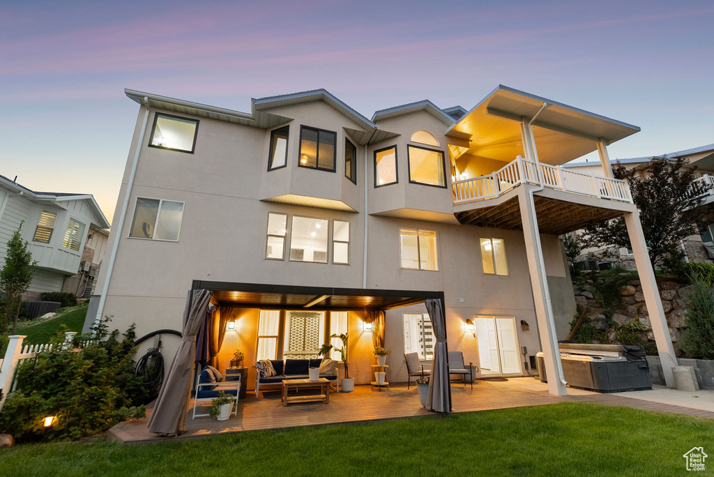 Rear view of property featuring outdoor lounge area, a hot tub, a balcony, stucco siding, and a patio area
