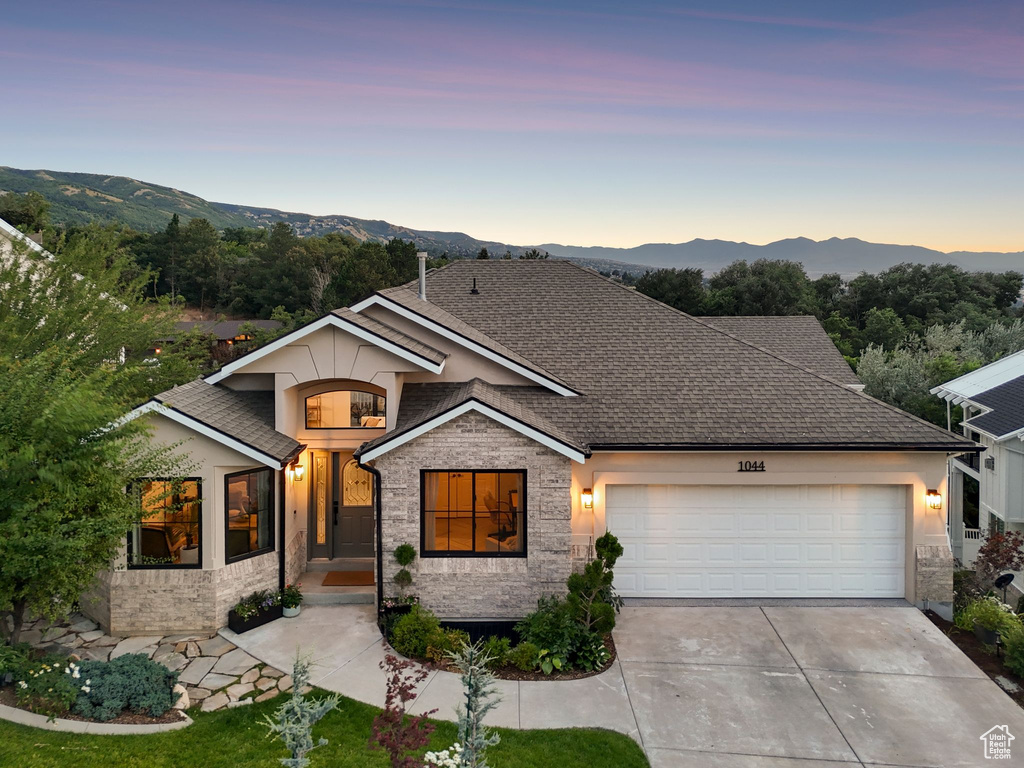 View of front of home with a garage, concrete driveway, a mountain view, and stone siding