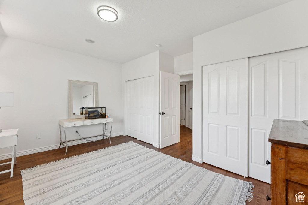 Bedroom featuring multiple closets, dark wood-style flooring, and a desk