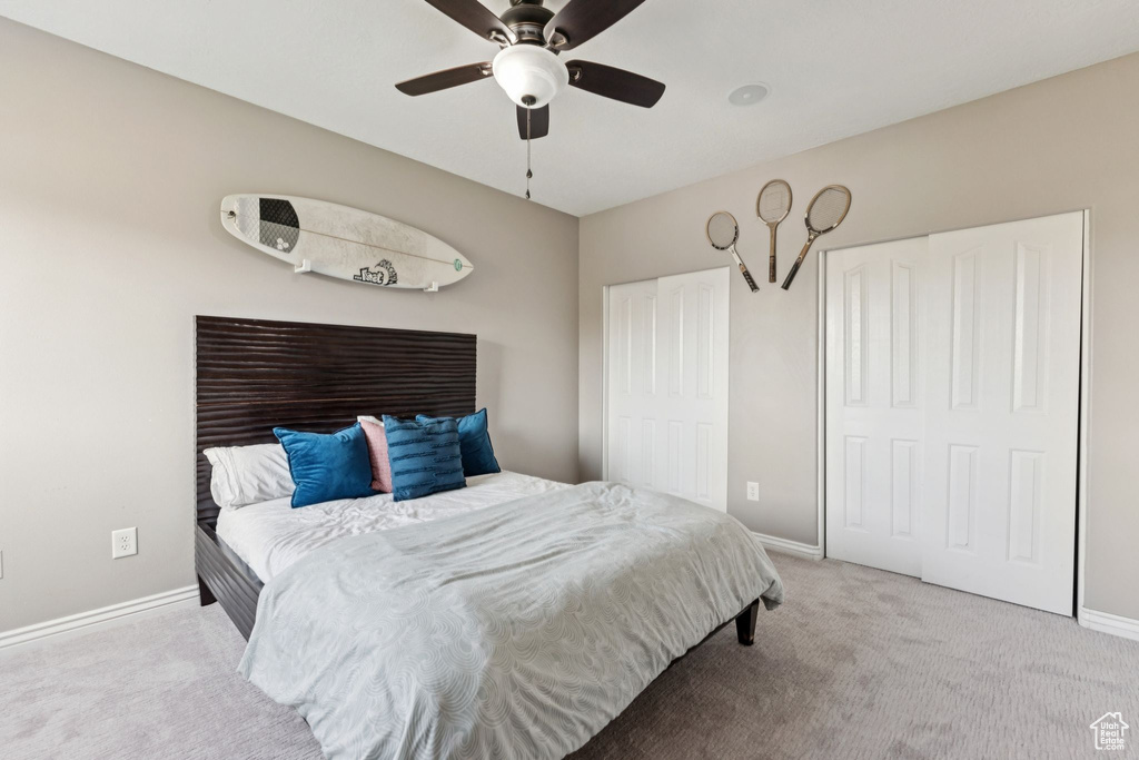 Carpeted bedroom with two closets and ceiling fan