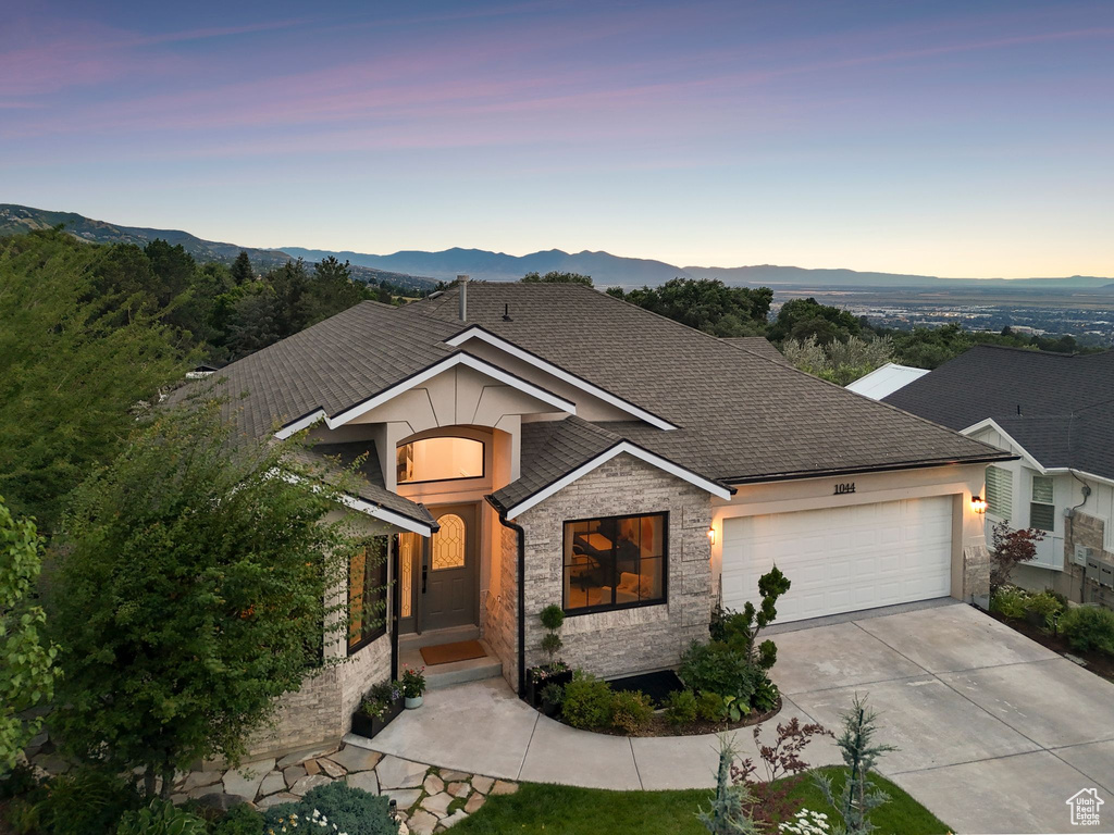 View of front of house featuring stone siding, an attached garage, concrete driveway, and a mountain view