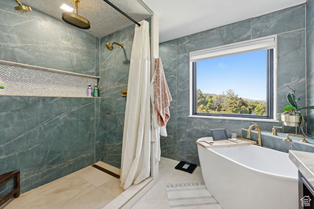 Full bath featuring tile walls, a tile shower, tile patterned flooring, and a soaking tub