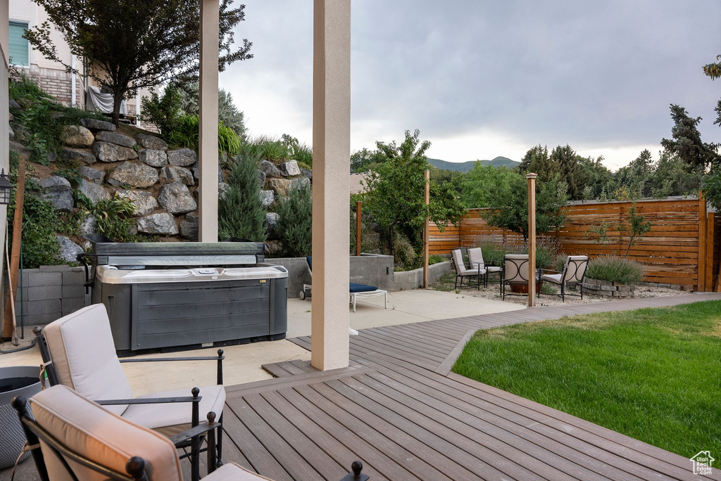 Wooden deck with a patio, a mountain view, and a hot tub