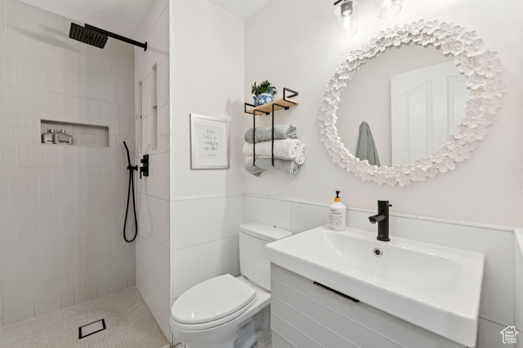 Bathroom with vanity, tiled shower, and tile walls