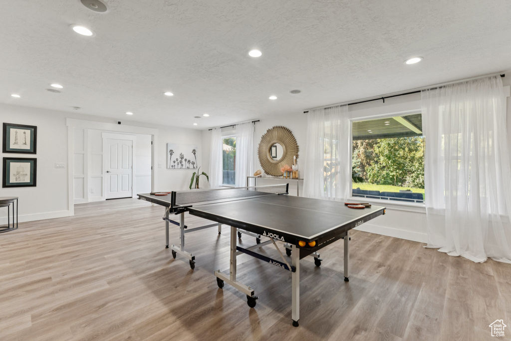 Game room with recessed lighting, light wood-type flooring, and a textured ceiling