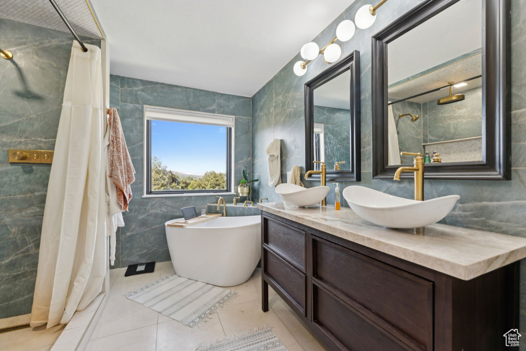 Full bathroom with tile walls, tiled shower, double vanity, a freestanding tub, and tile patterned floors