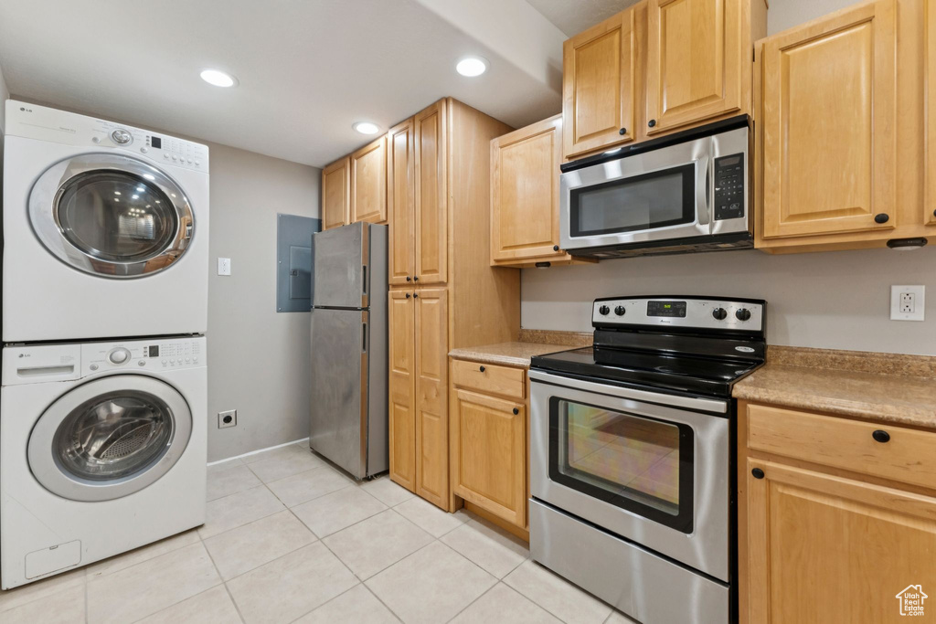 Kitchen featuring appliances with stainless steel finishes, estacked washer and dryer, recessed lighting, light tile patterned floors, and light countertops
