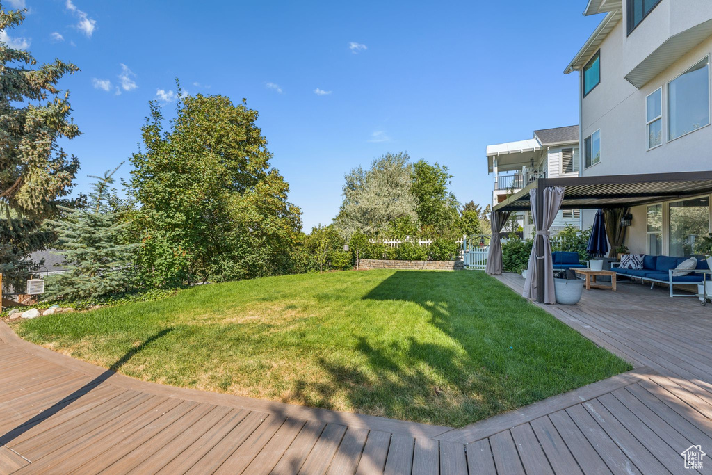 View of green lawn featuring an outdoor hangout area and a deck