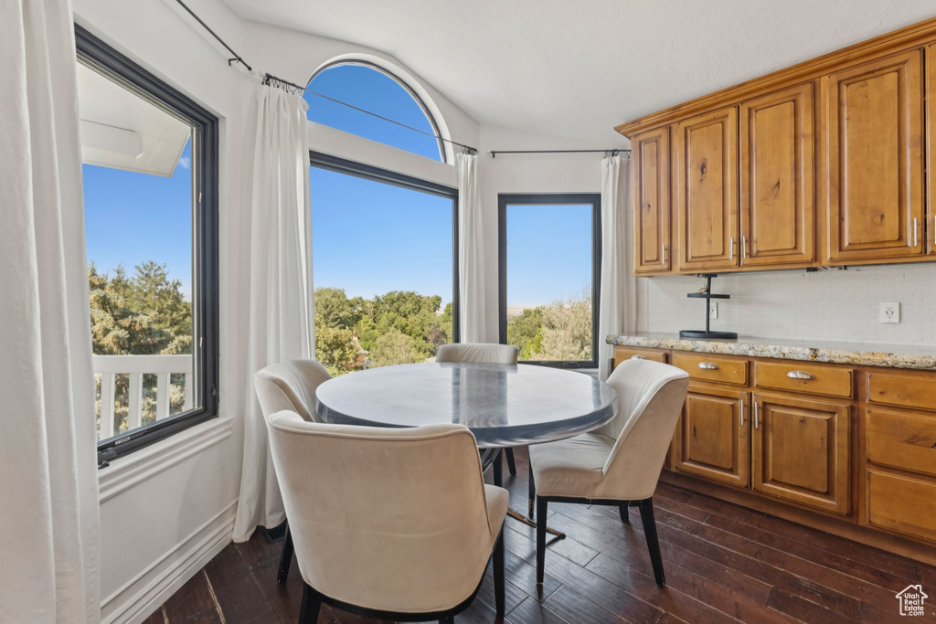 Dining area with vaulted ceiling and dark wood-style flooring