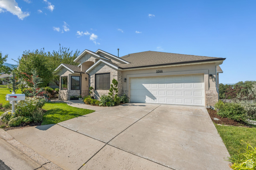 Ranch-style house featuring stone siding, an attached garage, driveway, and a front yard
