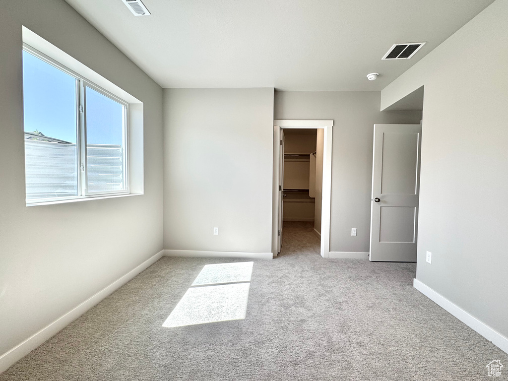 Unfurnished bedroom with carpet, a walk in closet, and a closet