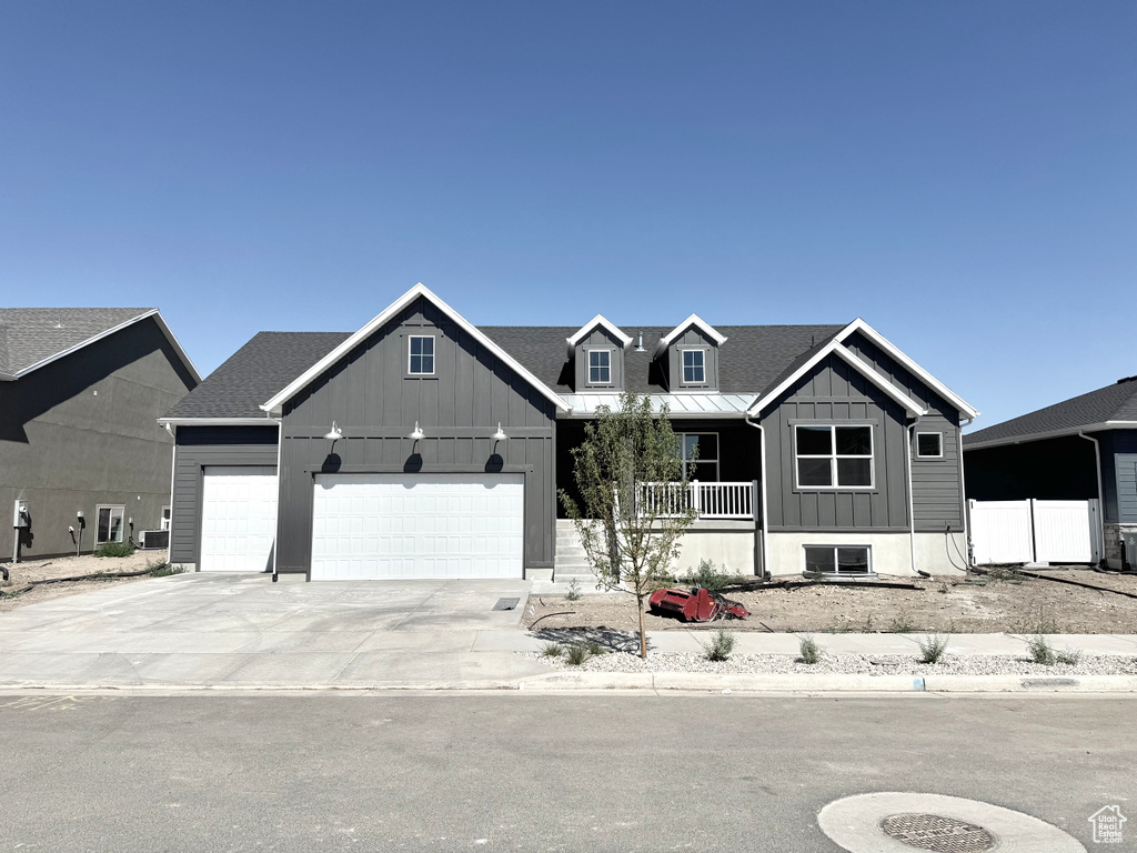 View of front of property with board and batten siding, covered porch, an attached garage, and driveway