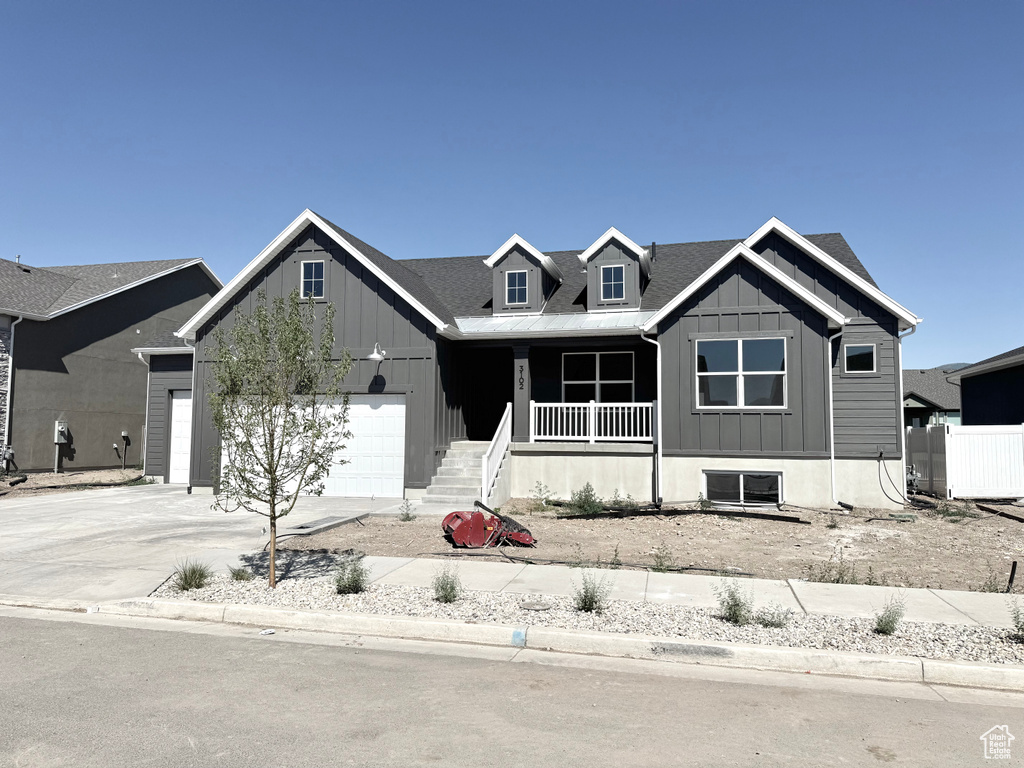 View of front facade featuring board and batten siding, a porch, concrete driveway, and a garage