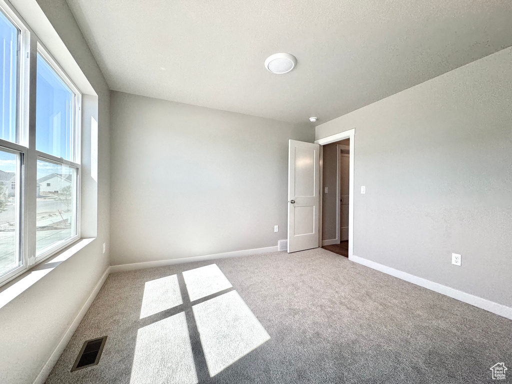 Carpeted spare room featuring baseboards