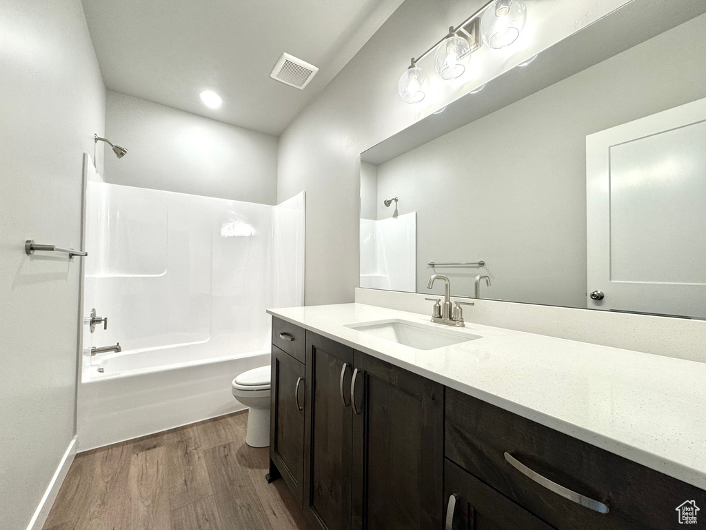 Bathroom with wood finished floors, shower / bathtub combination, and vanity