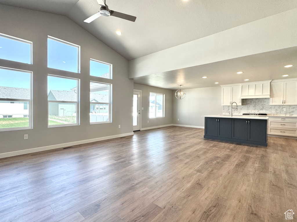 Unfurnished living room featuring high vaulted ceiling, ceiling fan, wood finished floors, and recessed lighting