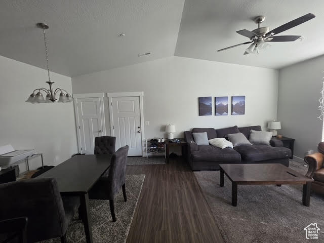 Living room with vaulted ceiling, a chandelier, dark wood finished floors, and a ceiling fan