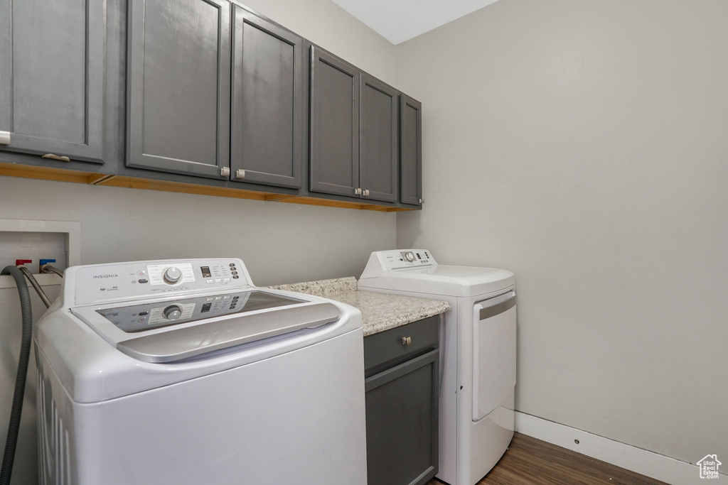 Washroom featuring cabinet space, independent washer and dryer, and dark wood-type flooring