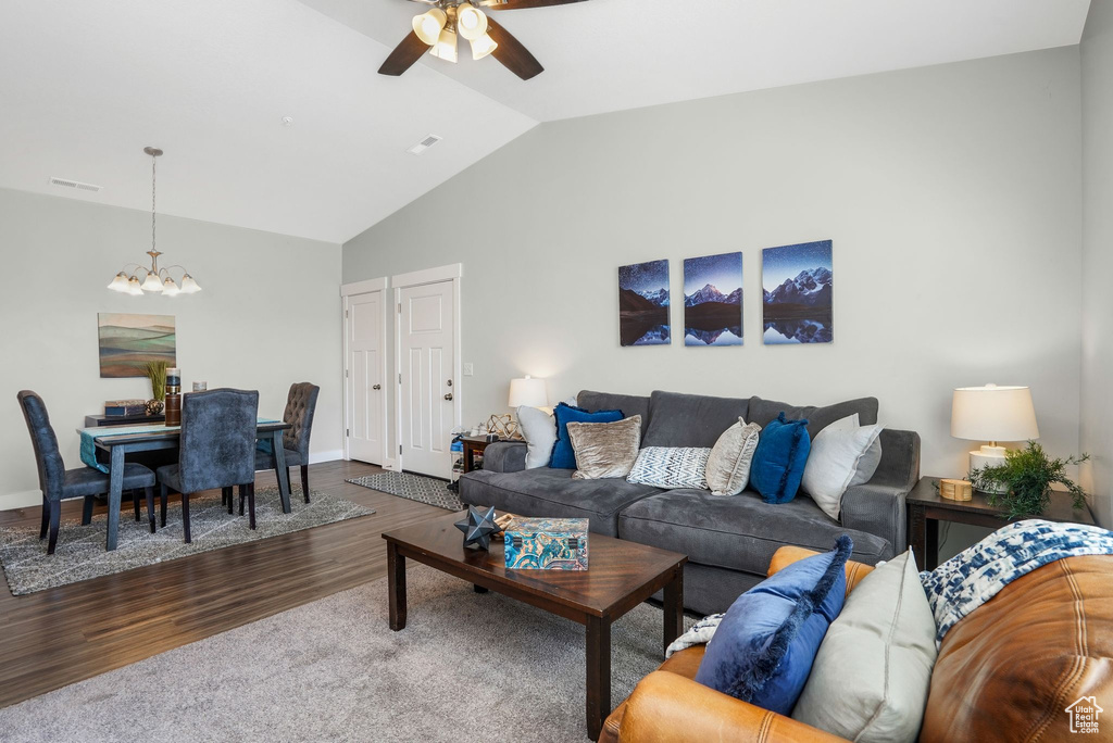 Living room with a chandelier, lofted ceiling, wood finished floors, and a ceiling fan