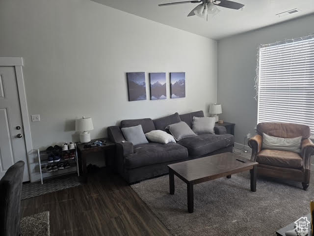 Living area featuring ceiling fan and dark wood-style flooring