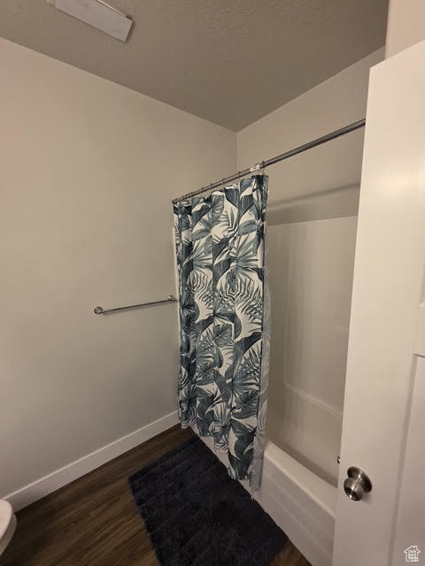 Bathroom with wood finished floors and shower / bathtub combination with curtain
