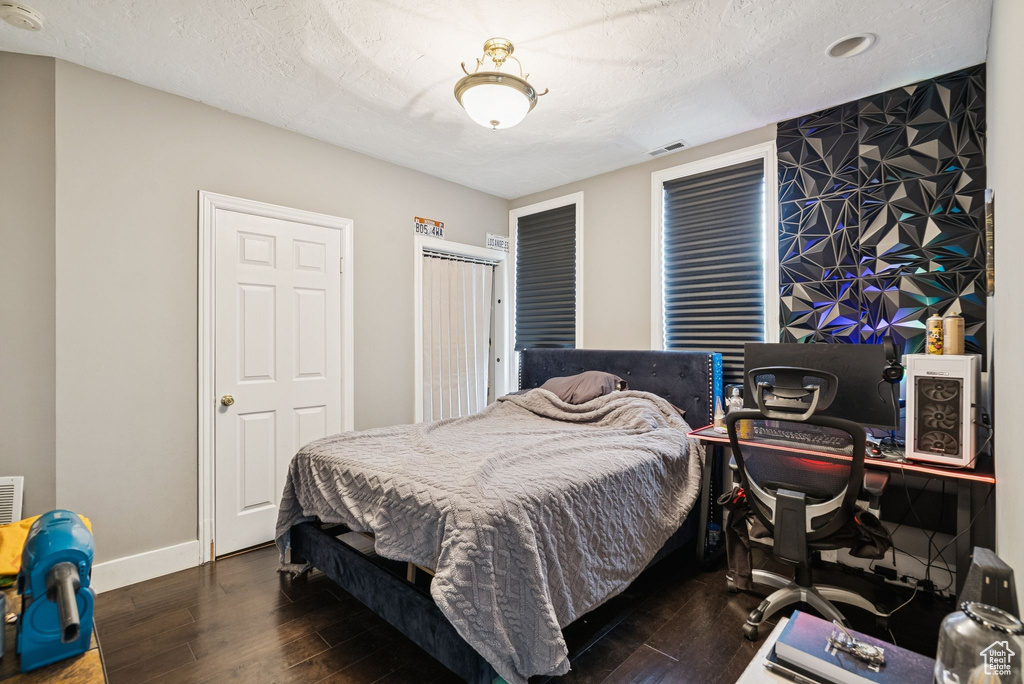 Bedroom with hardwood / wood-style flooring, an office area, and a textured ceiling