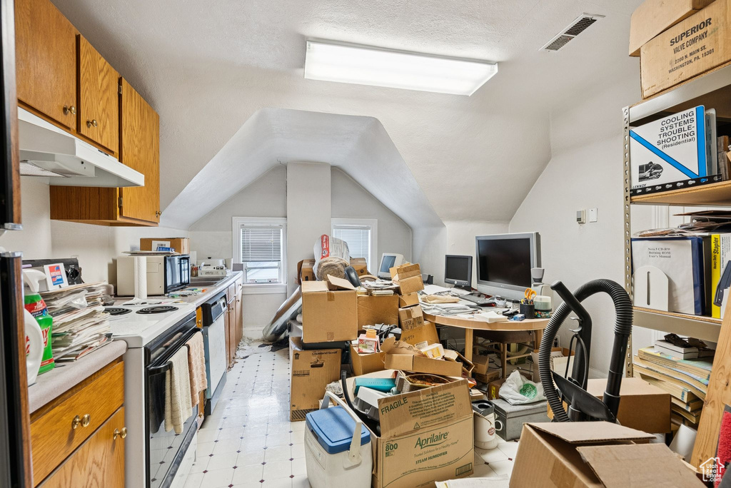 Office space featuring vaulted ceiling and light floors