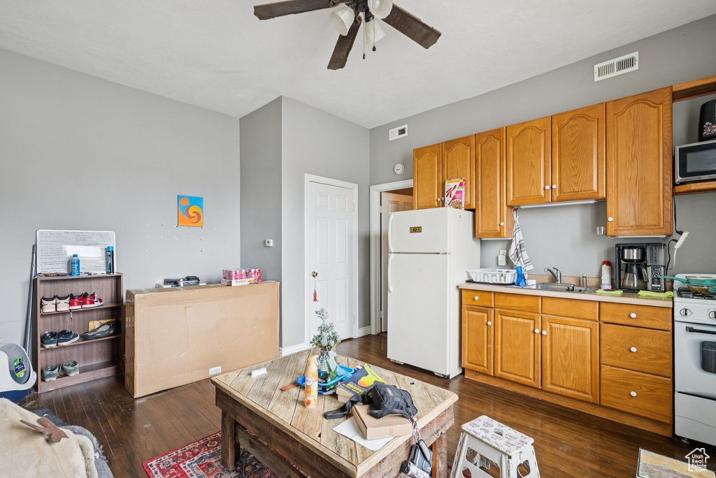 Kitchen featuring white appliances, a ceiling fan, dark wood-style flooring, and light countertops