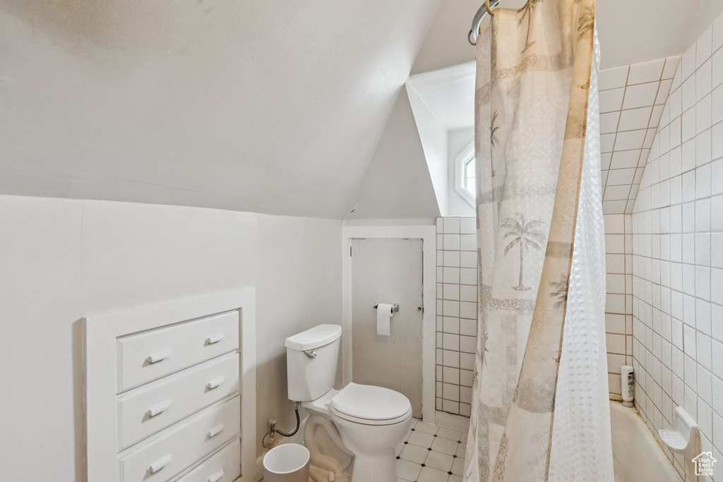 Full bathroom with lofted ceiling, shower / bath combination with curtain, and tile patterned floors