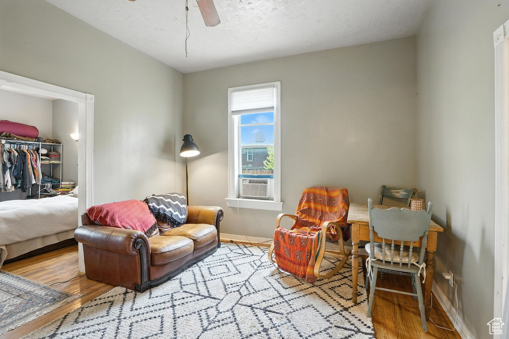 Living room with wood finished floors, cooling unit, and ceiling fan