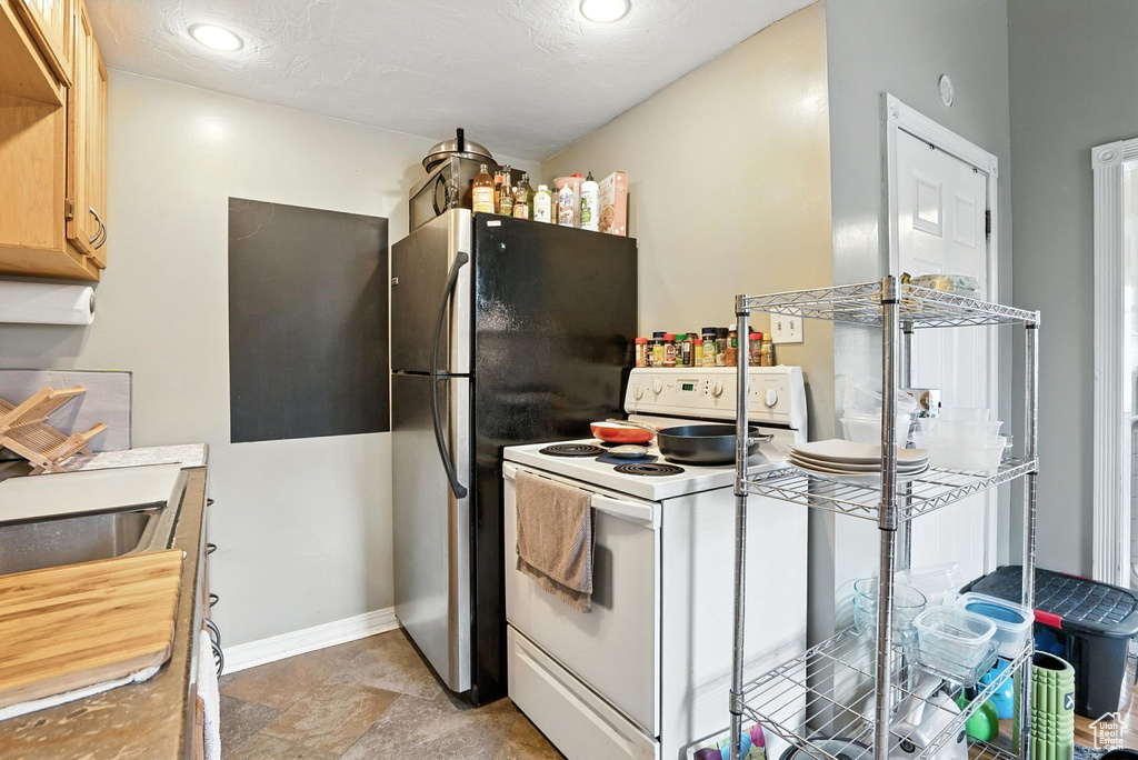 Kitchen with white electric range, freestanding refrigerator, and recessed lighting