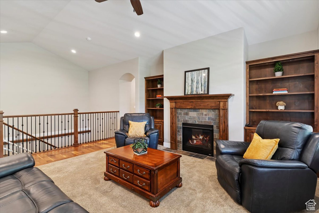 Living room with a ceiling fan, arched walkways, vaulted ceiling, recessed lighting, and a fireplace