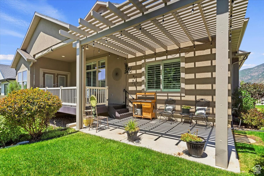 Back of house with a pergola, stucco siding, a lawn, and a patio