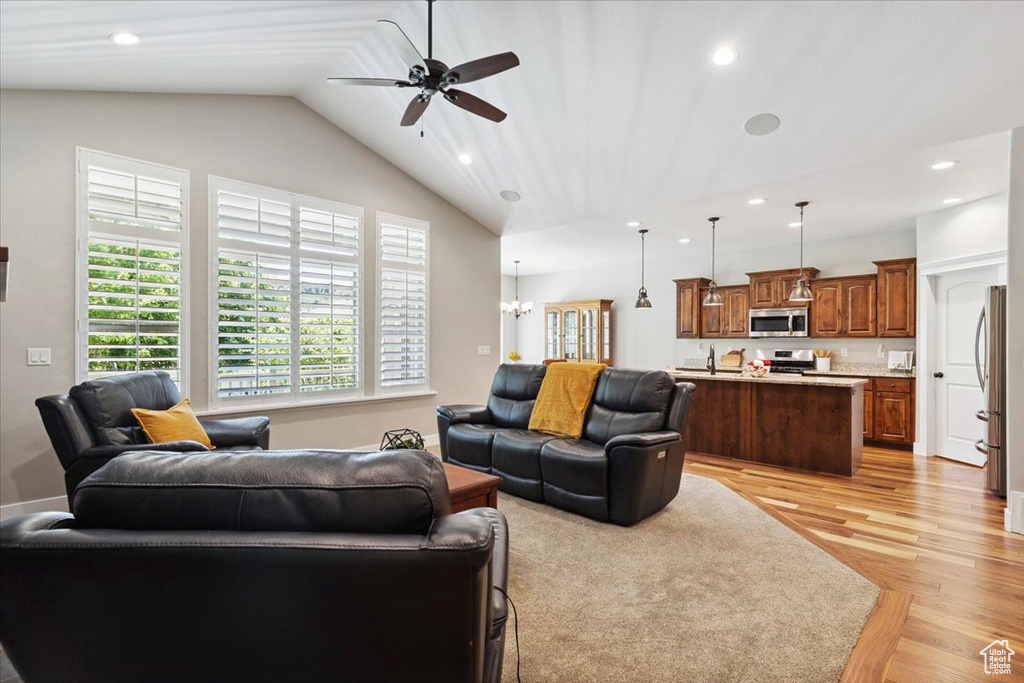 Living room featuring ceiling fan, light wood-type flooring, recessed lighting, lofted ceiling, and a chandelier