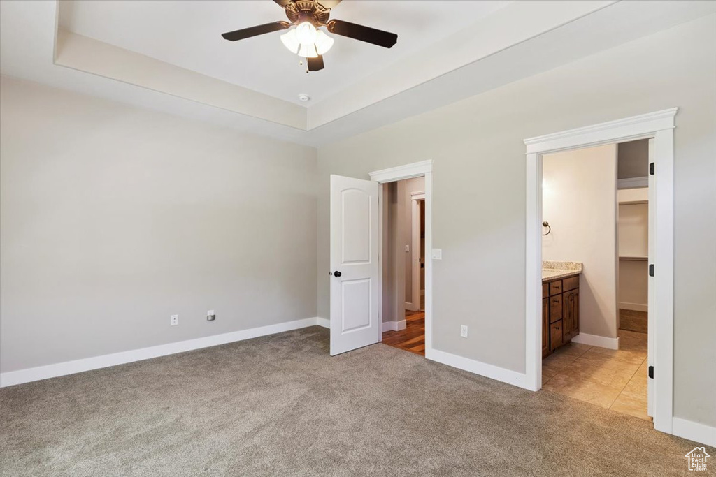 Unfurnished bedroom with light colored carpet, connected bathroom, and ceiling fan