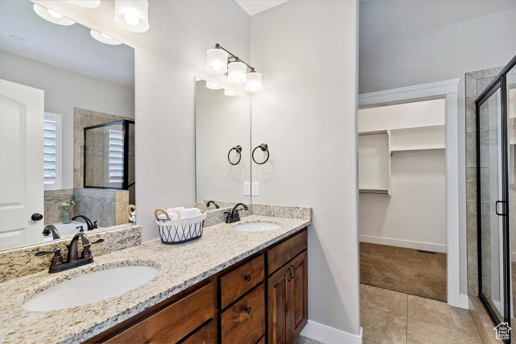 Full bath featuring a shower stall, a walk in closet, double vanity, and tile patterned flooring