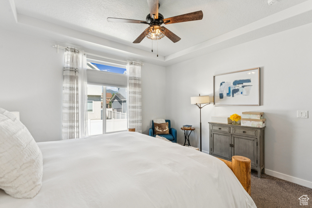 Bedroom with a tray ceiling, carpet, and ceiling fan
