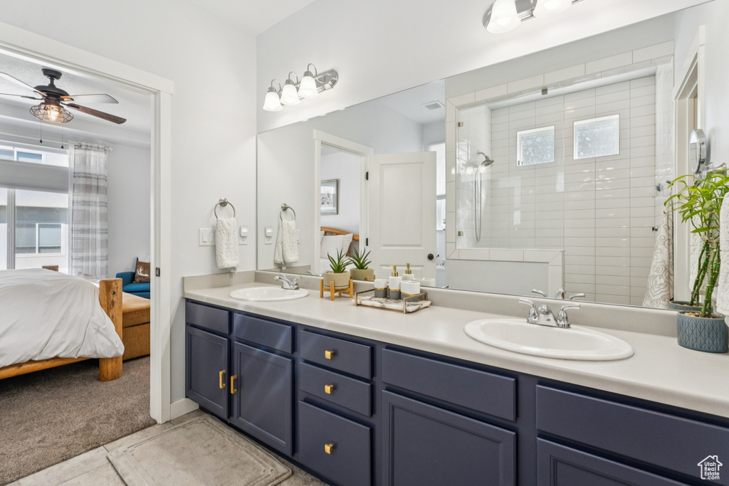 Ensuite bathroom with double vanity, ceiling fan, a tile shower, and tile patterned flooring