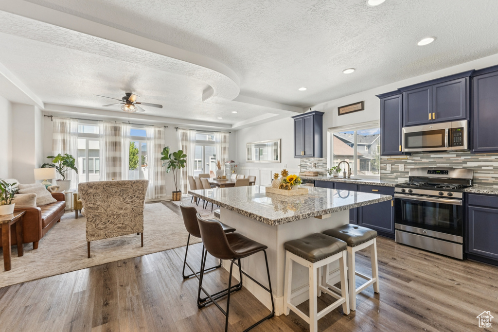 Kitchen with stainless steel appliances, a breakfast bar, a textured ceiling, plenty of natural light, and open floor plan