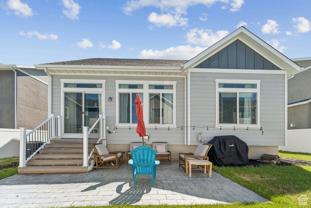 Back of property with board and batten siding, a patio area, and entry steps